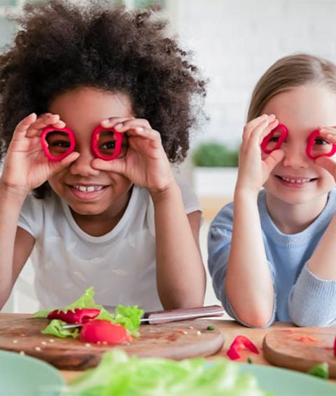 Kinder mit Gemüse für einen veganen Salat.