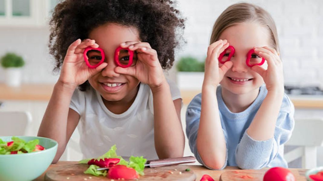 Kinder mit Gemüse für einen veganen Salat.